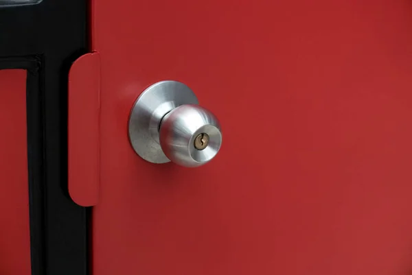 Red steel door with a stainless steel door knob.