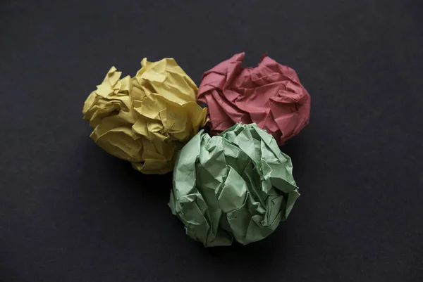 A colorful crumpled paper balls on a black background.