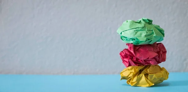 A stack of crumpled paper balls on a grey background with copy space.