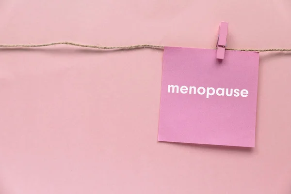 Pembe bir arka planda menopozla yazılmış ipte asılı duran pembe kağıt..