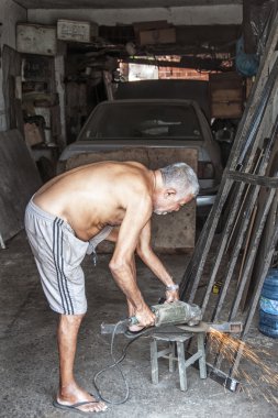 Elderly metalworker in his garage clipart