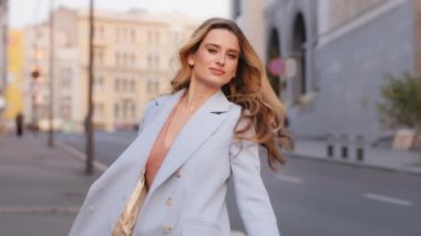 Modaya uygun mavi takım elbiseli güzel ve çekici bir iş kadını şehirde kameraya bakıyor. 30 'lu yaşlarda kaygısız bir beyaz kız model kız dışarıda sokakta dolanıyor.