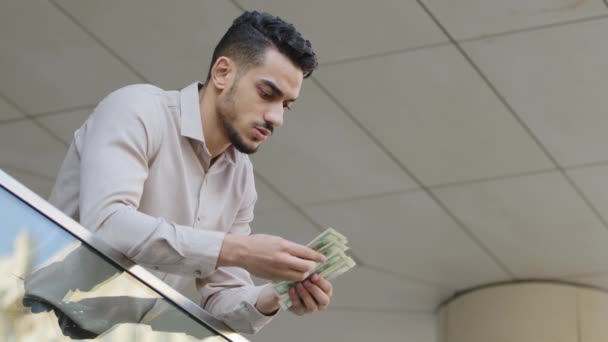 Młody arabski, odnoszący sukcesy biznesmen liczący pieniądze stojący na tarasie na balkonie. Sukces szefa facet wygrać z dużą ilością dolarów liczy dolary rachunki gotówkowe wynagrodzenie kalkulacyjne. Wymiana walut — Wideo stockowe