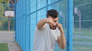 Genç boksör, boksör, güreşçi veya futbol fanatiği yumruklarını sıkmış el sallıyor, Arap İspanyol erkek atlet darbe gösterileri dövüş tekniklerini gösteriyor. Orta Doğulu Hintli adam stadyumda antrenman yapıyor.