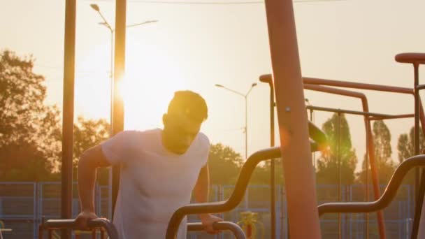 Sporty strong Arab man with well-developed biceps and trapezius muscles doing machine exercises during daily morning workout. Young energetic Middle Eastern Indian athletic guy works out in stadium — Stock Video