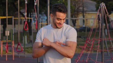 Milenyum sporu yapan Orta Doğu 'lu Arap adam, atletik başarılarıyla gurur duyan büyük pazılar gösteriyor. Genç Hintli sporcu sabah spor sahasında vücut kaslarını sunar.