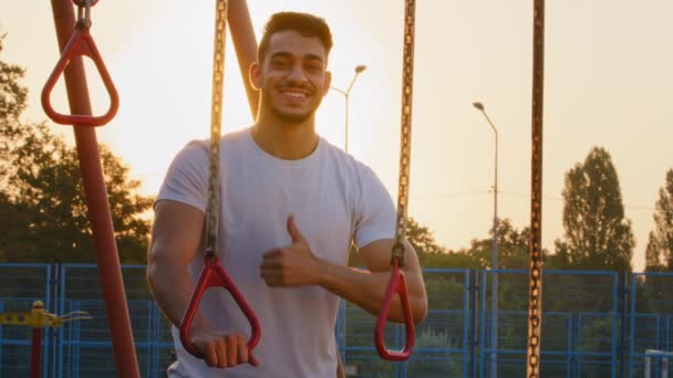 Sportlich kräftiger muskulöser arabischer Mann empfiehlt gesunden Lebensstil. Junger, energiegeladener indischer Sportler aus dem Mittleren Osten zeigt Daumen nach oben, glücklich mit Workout, effektiven Trainingsgeräten — Stockvideo