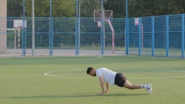 Gelecek vaat eden genç bir sporcu, enerjik bir Hintli sporcu, spor giyim kuşamında şınav çekiyor ve zıplıyor. Orta Doğulu futbolcu stadyumda antrenman yaparken ısınıyor, kardiyo egzersizleri yapıyor.