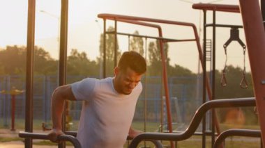 Yorgun, genç, Arap erkek sporcu barlarda antrenman yapıyor, göğüs kasları, pazılar, trisepsler. Milenyum sporcusu, spor giyimli orta doğulu Hintli sporcu yoğun sabah antrenmanını tamamladı.