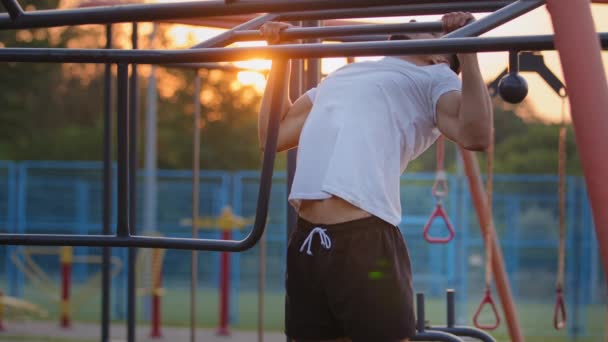 Mladý středovýchodní chlap dělá pull-up cvičení během cvičení na městském sportovním hřišti venku. Fešák silný atletický indický sportovní muž pumpování svaly trénink fitness a kulturistika koncept — Stock video