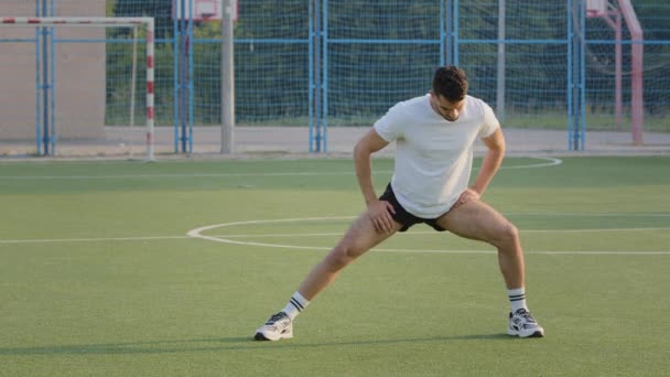 Maçtan önce iyi vücut eğitimi almış genç bir İspanyol atlet, esneme egzersizi yapıyor. Yazın spor giyinen Arap adam stadyumdaki antrenman sırasında egzersiz tekniği gösteriyor. — Stok video