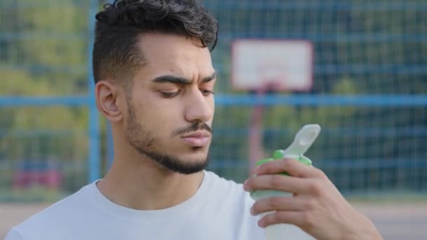 Close-up van de Midden-Oosterse indiaanse atleet latino loper lessen dorst na het joggen. Jonge Arabier kerel drinkt schoon zoet water uit sportfles tijdens dagelijkse training in de stad zomer stadion — Stockvideo