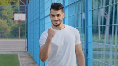 Genç enerjik, gülümseyen, kaslı sporcu şakası, yumruğunu gösterme, milenyum Hindistanlı adam, spor kıyafetlerinde pompalı pazılarıyla rakiplerini tehdit ediyor, kazanacağına söz veriyor. Stadyumda poz veren Orta Doğulu bir adam