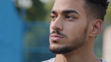 Kapalı erkek yüzü dışarıda. Bin yıllık ciddi, düşünceli, kahverengi gözlü, sakallı ve düşünceli İspanyol bir adam. Stadyumda poz veren kendine güvenen genç bir sporcu.