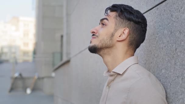 Portrét hispánského byznysu muž snivý vousatý stylový hezký spokojený inspirovaný arabský chlap muž stojí v blízkosti kamenné zdi ve městě venku dívá do nebe těší pohled odpočinku relaxační snění — Stock video