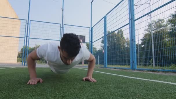 Młody energiczny silny umięśniony sportowiec milenijny Indianin z pompowanymi bicepsami w letniej odzieży sportowej robi ćwiczenia push up podczas treningu Bliskowschodni sportowiec ćwiczy trening ramion na stadionie — Wideo stockowe