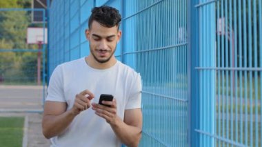 Orta Doğulu Hintli bir adam elinde telefonla mesaj yolluyor ya da mobil uygulamalar kullanıyor, akıllı telefondan sosyal medya uygulamalarını kontrol ediyor. Yazın spor giyim sektöründe cep telefonuyla oynayan Arap genç bir sporcu.