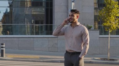 İspanyol iş adamı Arap adam, şehir binalarının arka planında durmuş cep telefonuyla konuşuyor uzaktan konuşma, kablosuz cihaz, cep telefonu iletişimini açık havada arıyor.