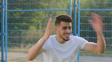Genç Arap Ortadoğu futbol koçu veya taraftarı oyun sürecini duygusal olarak gözlemliyor, oyunculara tavsiyelerde bulunuyor. İspanyol erkek sporcu futbol maçında el sallıyor, sonuçlardan hayal kırıklığına uğramış, gol.