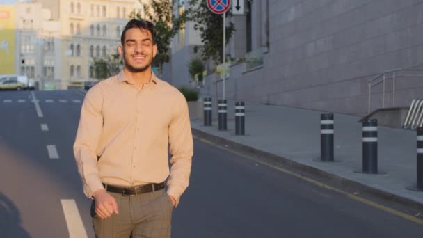 Успішний щасливий красивий іспанський бізнесмен посміхається арабський хлопець бос працівник арабський чоловік менеджер чоловік турист в офіційному одязі, що йде вулицею в новому старому місті, рухаючись по дорозі посміхаючись зубний — стокове відео