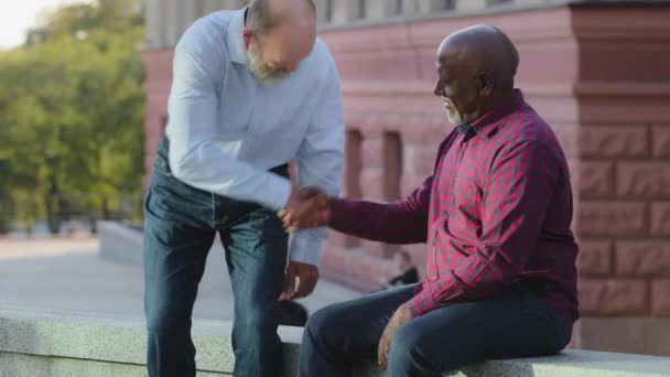 Amistosa diversidad feliz personas mayores colegas saludándose entre sí por apretón de manos. hombre afroamericano estrechando la mano europeo de pelo gris persona en la reunión, gerente haciendo mucho con el cliente — Vídeo de stock