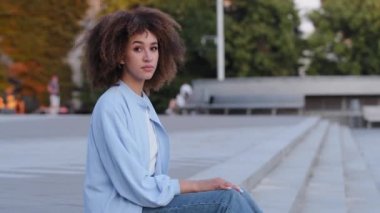 Üzgün üzgün, kıvırcık saçlı Afro saçlı Afro saçlı, üzgün bayan, şehir dışında oturmuş afiş anonsu yapan, sorunlarla ilgili yardım çağrısı yapan üzgün bir Amerikalı kadın.