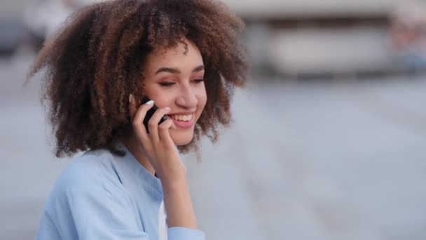 Позитивна бізнес-леді молода афроамериканська дівчина жінка говорить на мобільний телефон відповіді виклик використовує мобільний телефон для спілкування на відкритому повітрі міські консультації клієнт віддалено робить замовлення з пристроєм — стокове відео