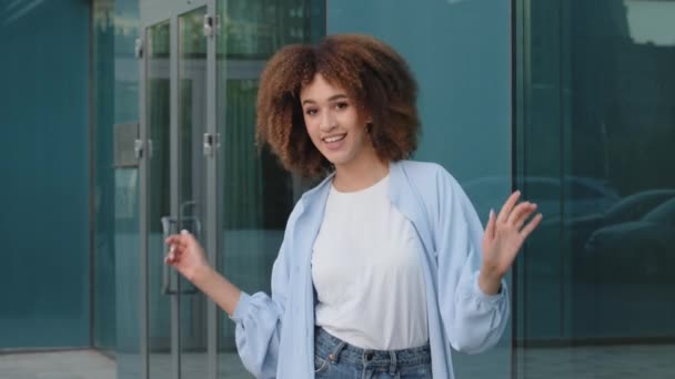 Young happy carefree african american mixed race ethnic woman afro girl with curly hair dancing dance to music doing rhythmic movements with hands moving singing song outdoors having fun in city — Stock Video