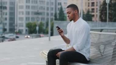 Zenci adam Bekleme randevusu sinirli Afro-Amerikan erkek afro-amerikalı erkek dışarıda oturur rahatsız hisseder. Etrafa bakar, birilerini ya da taksiyi gözetler ve geç saatlerde cep telefonuna bakar.