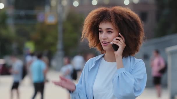 Портрет молодої вродливої дівчини змішаної раси афро-американської жінки-модель студентки стоять на самоті на вулиці в місті, відповідаючи на дзвінок, розмовляючи по мобільному смартфону, сміючись — стокове відео