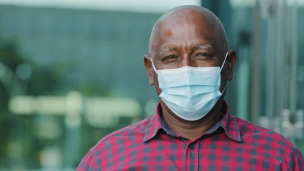 Retrato de perto idoso afro-americano homem em máscara facial proteger do coronavírus mostra gesto ok. Headshot de pessoa adulta madura em máscara facial contra o vírus da corona. Conceito de saúde vívida — Vídeo de Stock