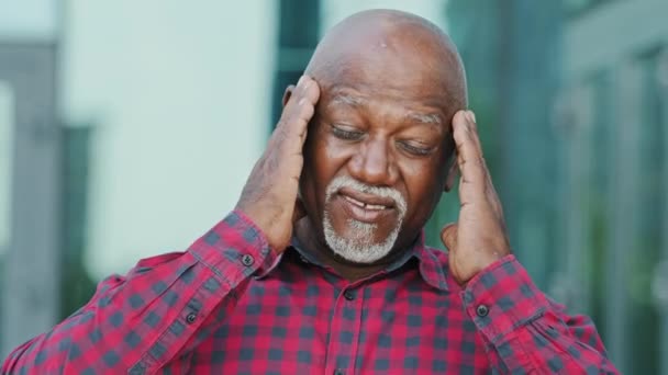Erwachsene reife Person im Rentenalter Stirnrunzeln ungesunde ältere afroamerikanische Mann mit grauem Bart berühren Massage Schläfen leidet an Migräne fühlt sich gestresst mit Kopfschmerzen Konzept Bild — Stockvideo