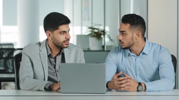 Két férfi kolléga, akik irodai beszélgetéseken dolgoznak együtt a munkahelyen, komoly üzletemberek, munkatársak, akik számítógépes üzleti projekt tervezéséről beszélgetnek, ötletbörze a vállalati csapatmunkában. — Stock videók