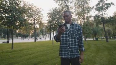Üzgün kızgın Afrikalı Amerikalı adam, turist erkek yabancıyı üzdü afro stresli adam, park yerinde duruyor, ormanın dışında, düşük pilli harita uygulaması konusunda endişeli cep telefonunda sorun yaşıyor.