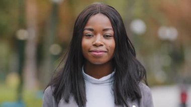 Ön manzara, karışık ırk genç bayan güzel model kadın yüzü siyah tenli afro genç bayan kameraya bakıp dışarı gülümsüyor. Parkta sağlıklı beyaz dişlerle gülümseyen Afrikalı Amerikalı kız.