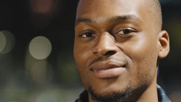 Férfi boldog portré afro-amerikai fiatal Y-generációs elégedett férfi áll a városban este város fények háttér nézi a kamera mosolygós foghullámzó fej egyetértésben válasz igen közelről — Stock videók