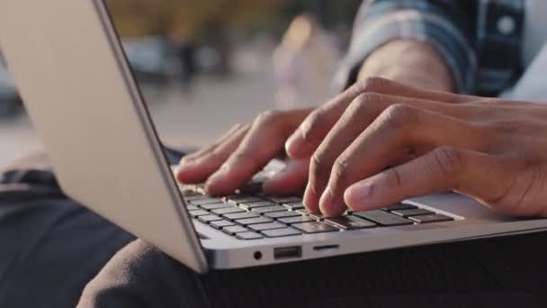 Közelkép férfi afro-amerikai munkás felhasználó kéz ujjak gyorsan gépelés laptop ülni a szabadban város, etnikai üzletember diák szakmai e-learning tanulmány munka pc szoftver technológia a parkban — Stock videók
