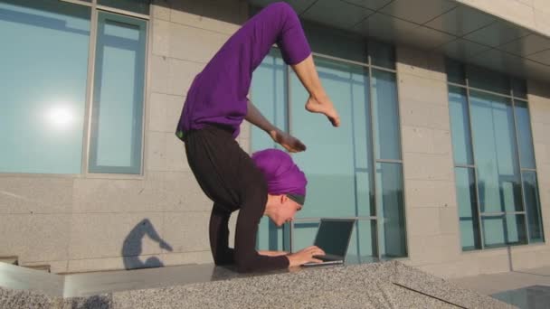 Occupé fille drôle dans hijab femme d'affaires utilisateur dame tapant sur ordinateur portable debout dans la main position debout asana debout à l'envers séance d'entraînement de yoga de travail avec ordinateur à distance e-learning dans la rue de la ville — Video