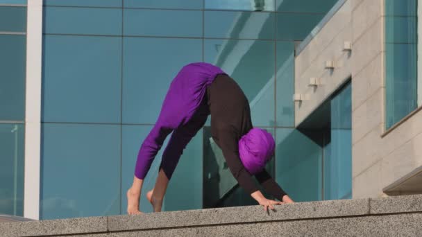 Şehirli arka planda yoga yapan tesettürlü güçlü kız Yogi bayan sporcusu surya namaskar asana duruş köpek yüzükoyun yatar açık hava sporu konsepti için egzersiz seti — Stok video