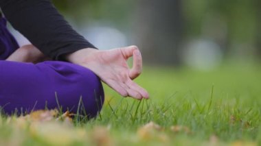 Jnana Mudra yoga pozisyonunda katlanmış kadın parmaklarını kapat Padmasana. Tanınmayan Budist kadın meditasyon yapıyor parkta çimlerin üzerinde oturuyor düşünceli meditasyon yapmaktan hoşlanıyor, uluslararası yoga günü.