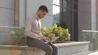 İspanyol işadamı dışarıda dizüstü bilgisayarla oturmuş ofis binasının yakınlarındaki uzak bir yerde çalışıyor. Genç Arap kullanıcı çalışanı, internette bilgisayar uygulaması yazıp sohbet ediyor.