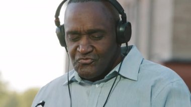 Aşırı neşeli, son sınıf öğrencisi, kulaklık takan Afrikalı Amerikalı iyi eğlenceler müzik dinleyerek rahatlayın mutlu, orta yaşlı, kulaklık takarak emekli olmuş, hafta sonu stresten uzak konseptin tadını çıkarın.