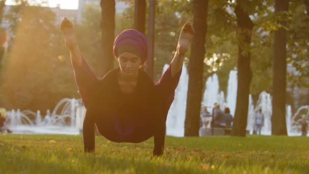 Sterke islamitische moslim indiaanse vrouw in hijab actieve meisje doen yoga in het park buiten trainingsoefeningen spannen spieren tonen acrobatische elementen asana vormt handstand goed stretching benen buiten — Stockvideo