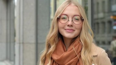 Güzel, kendine güvenen bir kadın kameraman kıza bakıyor sağlıklı beyaz dişli, mutlu, gözlüklü bir bayan sokak çekici öğrencisine poz veriyor.