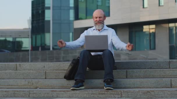 Idős nagyapa nyugdíjkorhatár nézi laptop monitor, integet kezét, érzi a boldogságot, örül. Idős európai férfi ősz szakállal nyert online lottó kapott jó hír, ünnepli a győzelmet — Stock videók