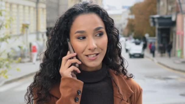 근접 한 여자 가 시내에서 핸드폰으로 통화하고 있어. 젊은 여자 아이는 스마트폰 현대 기기라고 대답하며 웃으며 세포간의 좋은 연결 고리를 채팅으로 얘기한다. — 비디오