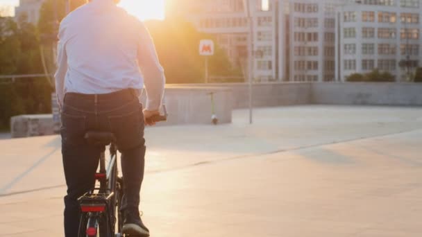 Rückansicht eines Stadtbewohners, der mit dem Fahrrad unterwegs ist. Ein erwachsener Erwachsener reist mit seinem persönlichen ökologischen Verkehrsmittel durch die Stadt. Umweltfreundliches Konzept zur Schadensminderung durch Abgase — Stockvideo