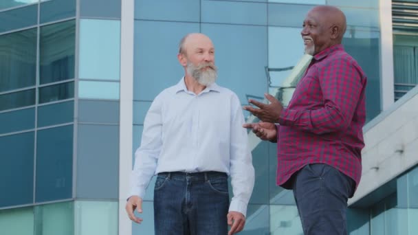 Zróżnicowany przyjazny mężczyzna partnerzy koledzy lub przyjaciele rozmawiający spacery na świeżym powietrzu starsi afrykańscy i kaukascy biznesmeni omawiający wspólny projekt uśmiechający się dzielenie się wiadomościami spotkanie podczas przerwy — Wideo stockowe