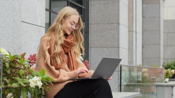 Framgångsrik attraktiv affärskvinna som arbetar på laptop i staden kaukasiska flicka student e-lärande utomhus dam skriva sitter på terrassen kvinnlig frilansare chatta med kunden med hjälp av trådlös dator — Stockvideo