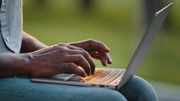 Afrikansk man professionell upptagen arbetare frilansare bloggare, användare skriva på bärbar dator sitta utomhus nära tangentbord och fingrar. Entreprenör arbete med trådlös dator netbook, programvara, teknik koncept — Stockvideo
